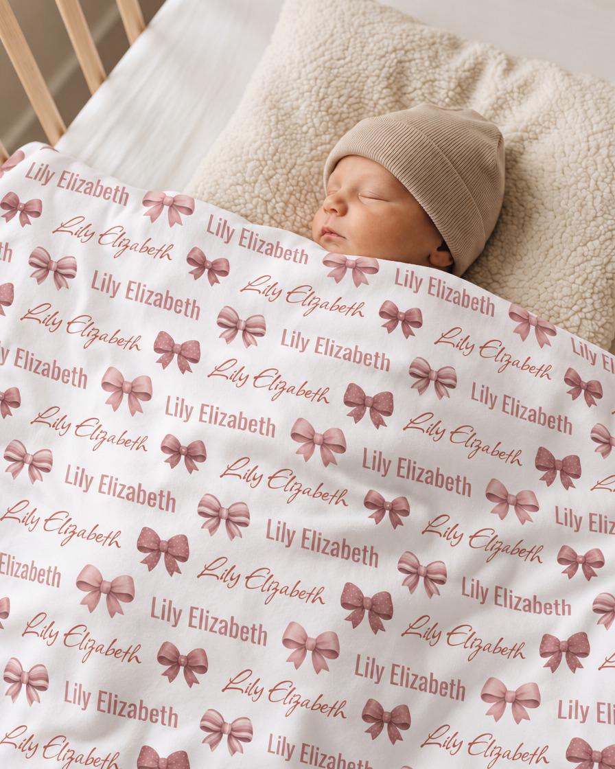 Personalized bow baby blanket draped over infant