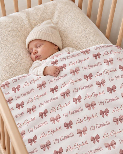 Sleeping baby under personalized bow name blanket