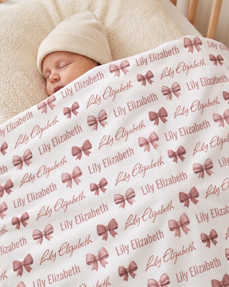 Newborn wrapped in personalized pink bow blanket